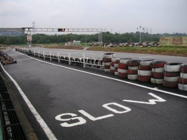 Image of a race track with the word SLOW painted on the pavement