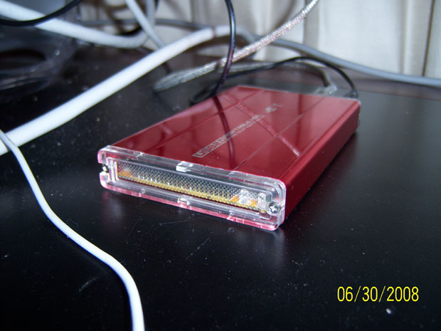 A red aluminum external hard drive enclosure with interfaces for both Firewire and USB